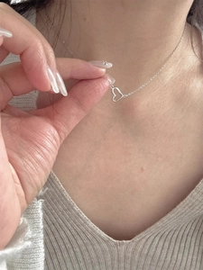 Dettaglio di una collana con ciondolo a cuore d'argento indossata da una donna