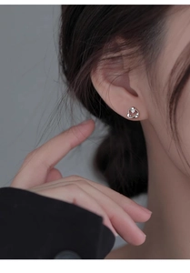 Close-up of minimalist silver heart-shaped stud earring with a sparkling zircon inlay