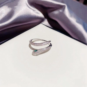 Macro shot of silver snake ring featuring white zircons and emerald green stone eyes