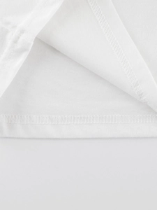 Détail de couture à double aiguille sur l'ourlet d'un t-shirt blanc en coton enfant