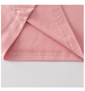 Macro shot of pink knit fabric hem showing neat overlock stitching on children's T-shirt