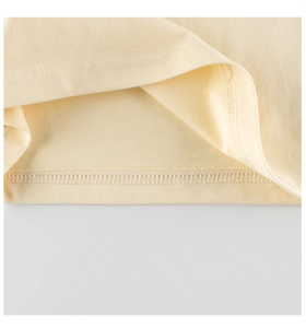 Close-up of high-quality overlock stitching on the hem of a yellow cotton t-shirt