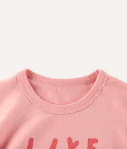 Détail du t-shirt rose en coton avec encolure côtelée et imprimé de lettres rouges