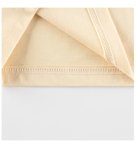 Macro shot of double-needle hem stitching and overlock seams on beige cotton girls' tee