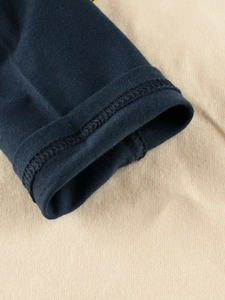 Close-up of navy blue and beige contrast color stitching on girls long sleeve cotton shirt