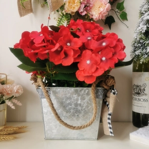 Detail of red geraniums in galvanized metal bucket with rustic burlap rope and plaid bow