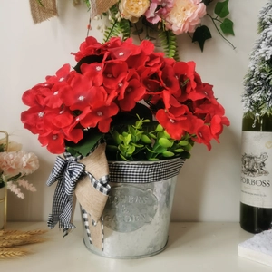 Detail of red geranium hanging basket with galvanized metal pot and buffalo plaid bow