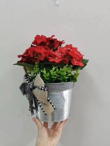 Detail of red artificial geraniums in a vintage galvanized metal bucket with bow