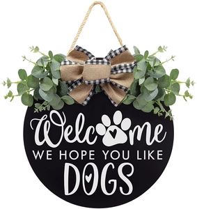 Detail of wooden welcome sign with green eucalyptus leaves and checkered bow decoration