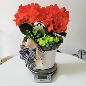Detail shot showing the weight of the red artificial flower basket on a digital scale