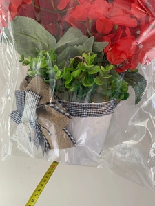 Detail view of artificial red geranium in white pot with buffalo plaid bow and tape measure