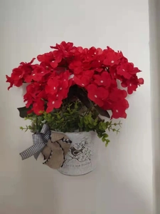 Close-up of red artificial geraniums in a white metal bucket with a buffalo check bow