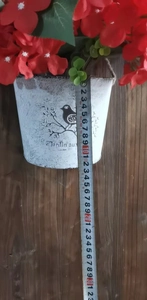 Close-up measuring 11cm height of a vintage white planter with red artificial flowers