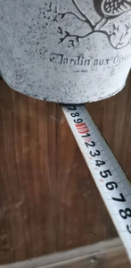 Detail showing height measurement of a vintage white metal garden bucket with bird motif