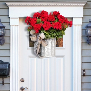 Christmas hanging basket with red geraniums and black-white plaid bow on white wood door
