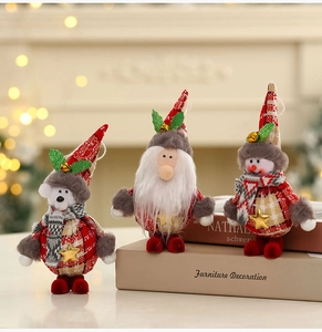 Detailed close-up of plush Christmas ornaments with red plaid fabric and golden bell accents