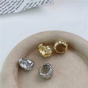 Detail of classic gold and silver croissant twist hoop earrings on a decorative tray