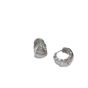 Detail of silver twisted croissant hoop earrings with a modern minimalist texture