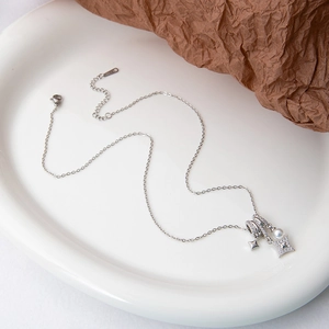 Macro shot of silver necklace with star pendants and pearl on white decorative tray