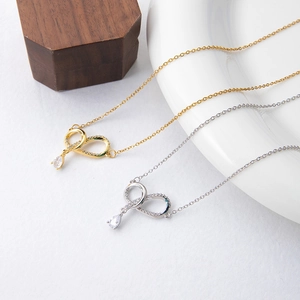 Elegant gold and silver bow necklaces with teardrop zircon pendants on white background