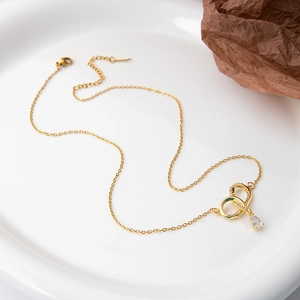 Detail of gold necklace featuring double ring pendant with zircon and teardrop stone