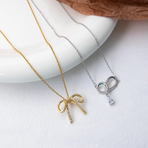 Detailed view of zircon-studded bow and teardrop crystal pendants on elegant necklaces