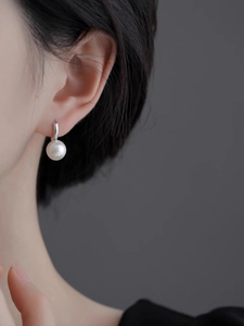 Gros plan d'une boucle d'oreille élégante en perle et argent portée par un mannequin