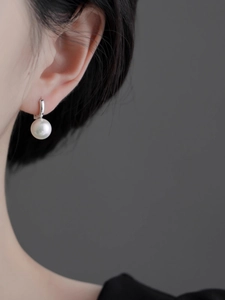 Gros plan d'une boucle d'oreille en perle blanche de qualité avec créole argentée