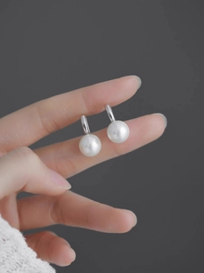 Détail de boucles d'oreilles élégantes en perles blanches rondes avec crochets en métal