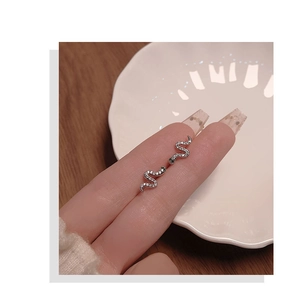Close-up of silver snake stud earrings with pavé crystals held by hand for size
