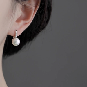 Boucle d'oreille perle minimaliste en argent portée par un mannequin élégant