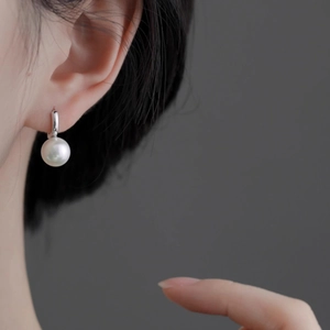 Élégantes boucles d'oreilles perles blanches avec crochets argentés portées par un mannequin