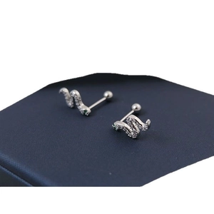 Silver snake ear studs with green eyes and white crystals on blue jewelry box