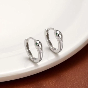 Créoles serpent en argent poli avec yeux en zircon vert sur fond minimaliste chic