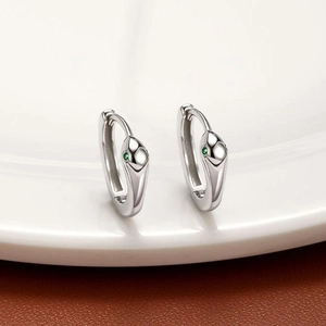 Vue macro de boucles d'oreilles serpent en argent avec yeux en zircon vert sur porcelaine