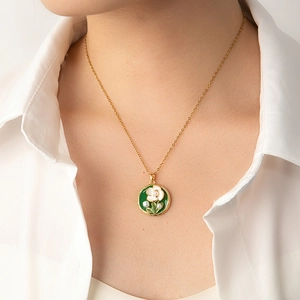 Gros plan d'un collier en émail à motif floral vert et perles porté par un mannequin
