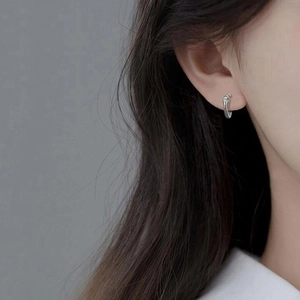 Boucle d'oreille ear cuff en argent à texture lave portée par un mannequin, style moderne