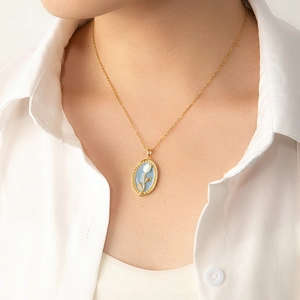 Gros plan d'un collier vintage doré avec pendentif fleur en émail bleu sur modèle
