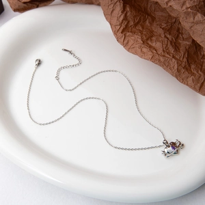 Detailed view of silver necklace featuring a purple heart-shaped planet pendant with star
