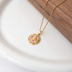 Détail d'un collier vintage doré avec pendentif fleur en émail rose et perles
