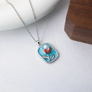 Detailed macro view of the blue enamel tulip pendant and silver necklace chain