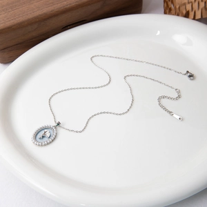 Close-up of silver-tone oval pendant with ginkgo leaves and white faux pearls border