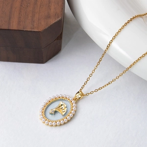 Detail of gold necklace with ginkgo leaf enamel pendant and pearl border decoration