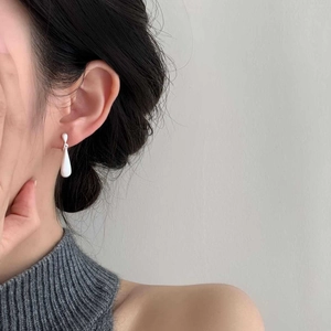 Minimalist silver long teardrop earrings with brushed finish shown on a female model