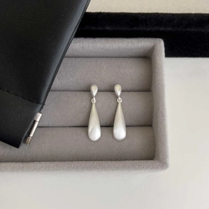 Minimalist silver brushed teardrop earrings displayed in a grey velvet jewelry box