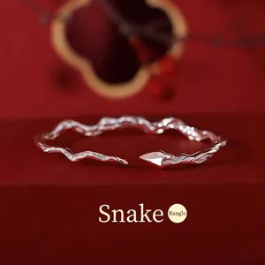 Adjustable S925 silver snake bangle with hammered texture on a festive red background