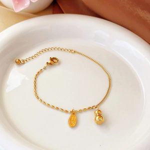 Golden gourd anklet with lucky tag and dual-chain design on a white ceramic plate