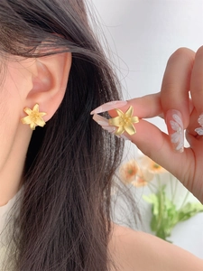 Macro detail of matte gold lily flower stud earring showing intricate petal textures