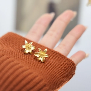 Macro shot showing detail of matte gold lily earrings with brushed metal texture