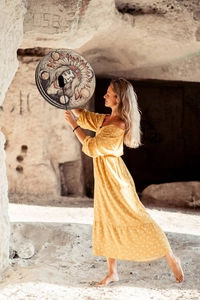 Artistic detail of native style shaman drum with hand-painted portrait in cave light